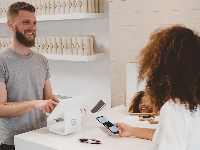 Client effectuant un paiement sans contact par smartphone en caisse de magasin